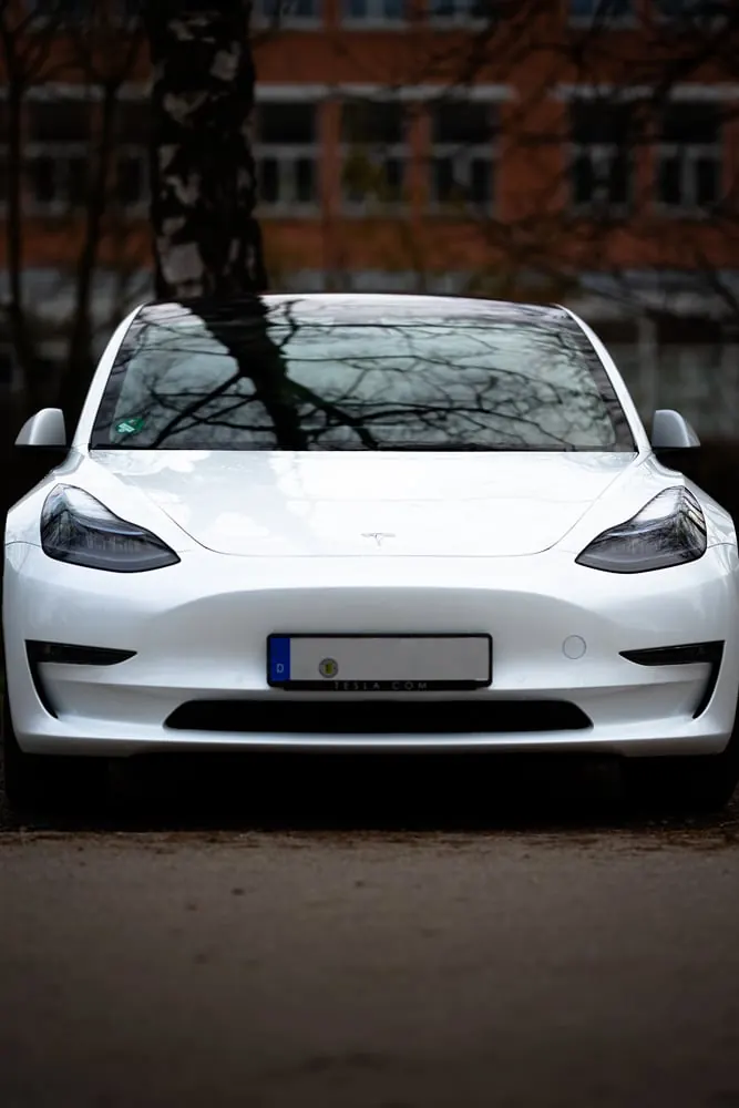 Weißes Tesla Model 3 vor Backsteinfassade