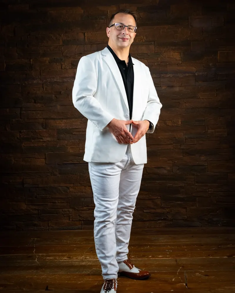 Ganzkörperportrait im weißen Sakko vor Backsteinwand