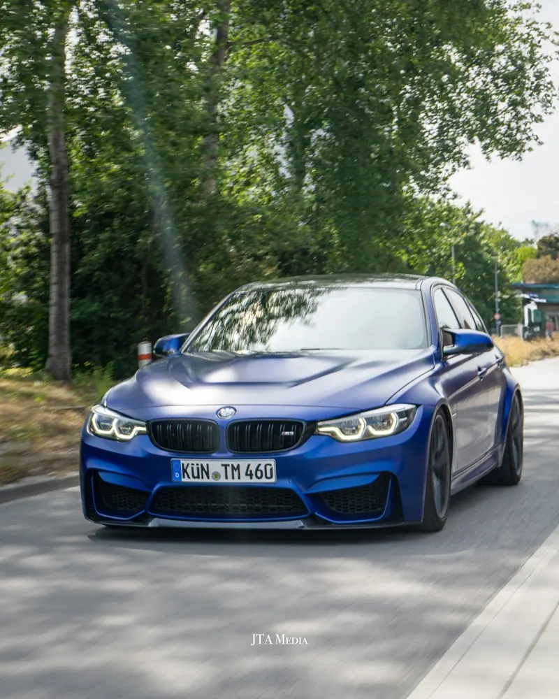 Blauer BMW M4 auf einer Allee