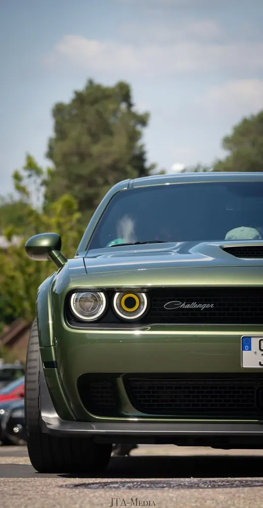 Grüner Dodge Challenger zwischen Bäumen